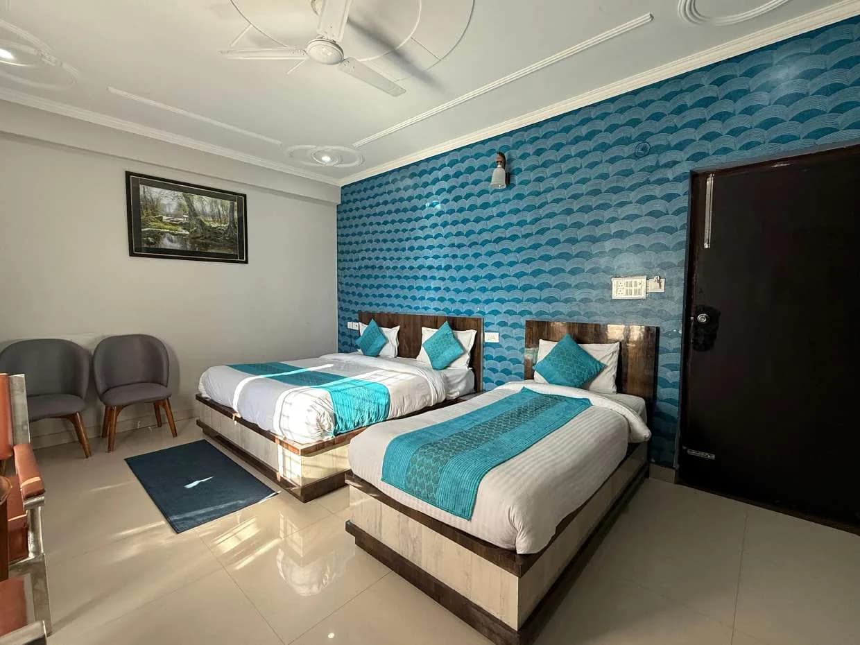 Room with two beds in front of a blue wave-pattern wall