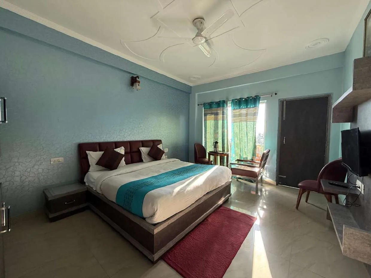 Light-blue room with double bed, tea table and curtained full-height window