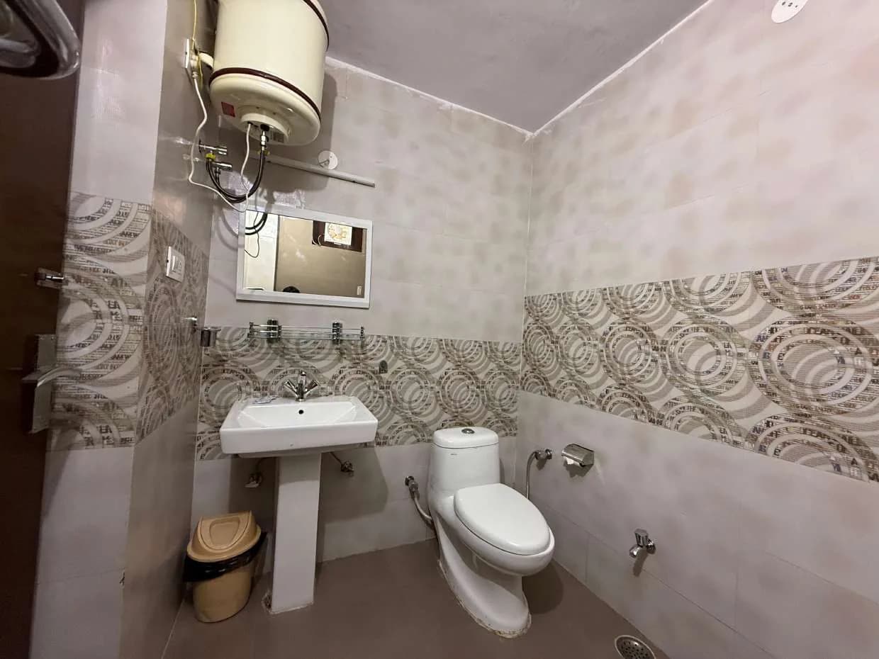 Bathroom with pedestal basin, wall-mounted geyser and patterned tile band